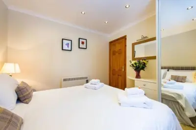 a bedroom with two beds and a mirror at Osprey Lodge with river and mountain view in Crianlarich