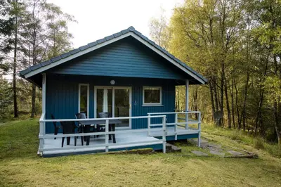 a blue tiny house with a large porch at Otter with mountain view and enclosed decking in Crianlarich