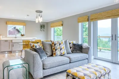 a living room with a couch and a table at Stunning 5 star lodge with loch and mountain views in Crianlarich