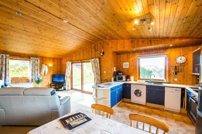 a kitchen and living room with a couch and a table at Raven Lodge with beautiful views of Loch Dochart in Crianlarich