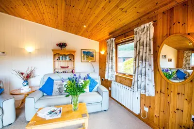 a living room with a couch and a table at Raven Lodge with beautiful views of Loch Dochart in Crianlarich