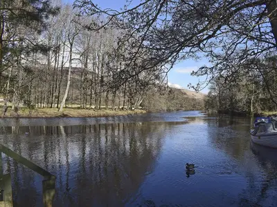 a boat on a river with a duck in the water at Can Duran in Killin