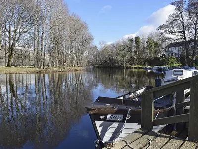 a boat is docked at a dock on a river at Can Duran in Killin