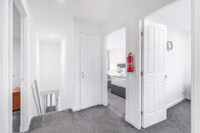 a hallway with two white doors and a bedroom at Prime Commuter Executive Apartment Dunfermline in Dunfermline