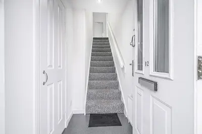a hallway with a staircase with white walls and a door at Prime Commuter Executive Apartment Dunfermline in Dunfermline