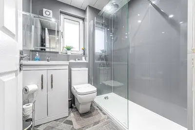 a bathroom with a toilet and a glass shower at Prime Commuter Executive Apartment Dunfermline in Dunfermline
