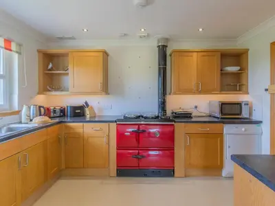 a kitchen with wooden cabinets and a red stove top oven at The Potting Shed in Challoch