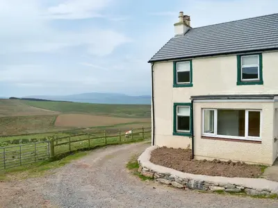 a house on a dirt road next to a fence at High Ranachan in Campbeltown