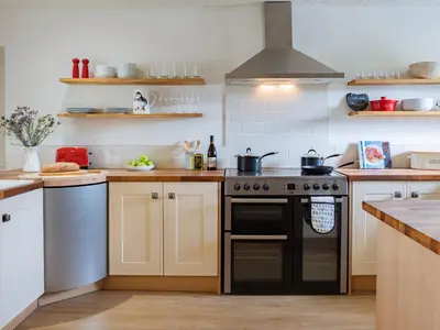 a kitchen with a black stove and white cabinets at High Ranachan in Campbeltown
