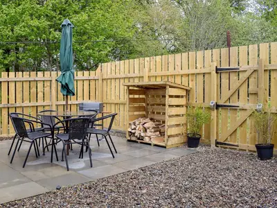 a patio with a table and chairs and a wooden fence at Anemone in Kenmore