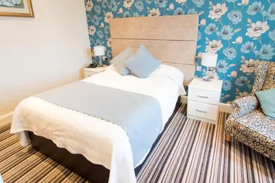 a bedroom with a bed and a chair at South Beach Hotel in Troon