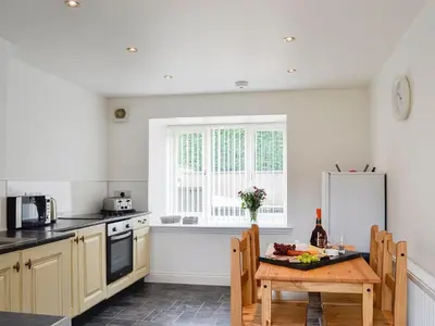 a kitchen with a wooden table and a window at Kirroughtree Steading 1 - Uk5859 in Newton Stewart