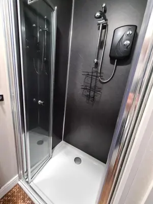 a shower stall with a glass door and a shower at Coel Ila in Benderloch
