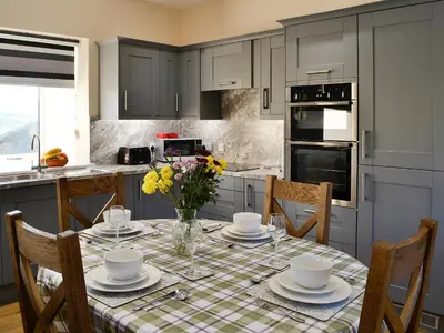 a kitchen with a table with plates and flowers on it at Liftingstane Dairy Cottage in Closeburn