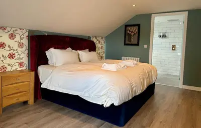 a bedroom with a large bed with white sheets at Altskeith Country House in Aberfoyle