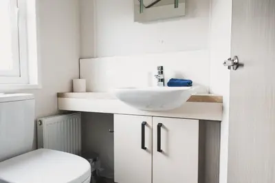 a white bathroom with a sink and a toilet at Atlas Ovation Lodge in Auchterarder