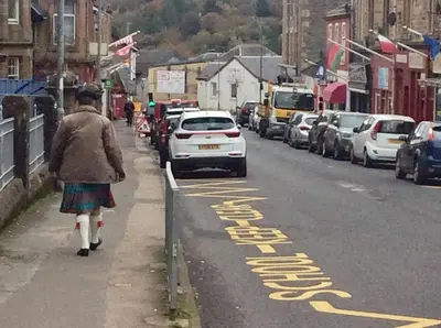 a woman walking down a street with a car parked at DUNOON - TOWN CENTRE HOLIDAY HOME APARTMENT in Dunoon