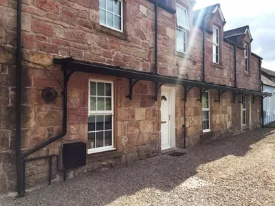 an old brick building with white doors and windows at The Clacks Rustic Abode in Tillicoultry