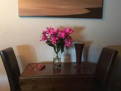 a vase of pink flowers sitting on a wooden table at The Clacks Rustic Abode in Tillicoultry