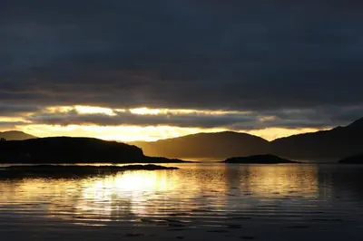 a sunset over a body of water with mountains at Lurach House in Port Appin