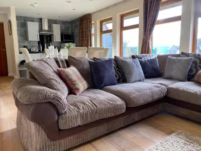 a brown couch with pillows in a living room at Balmaha Lodges and Apartments in Balmaha