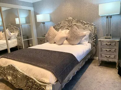 a bedroom with a silver bed with pillows and mirrors at Ayrs and Graces - Luxury Bed and Breakfast in Ayr
