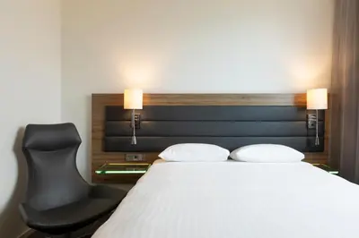 a bedroom with a bed and a black chair at Moxy Glasgow Merchant City in Glasgow