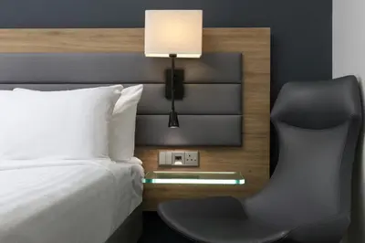a bedroom with a bed with a chair and a lamp at Moxy Glasgow Merchant City in Glasgow