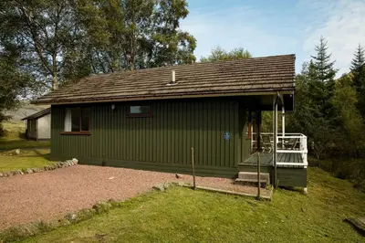a small green building with a porch and a balcony at 2 bedroom lodge with free WiFi and mountain view in Crianlarich