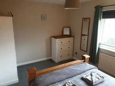 a bedroom with a bed and a dresser and a mirror at Oldwood Place Townhouse in Livingston
