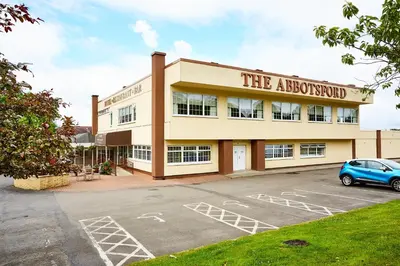 a building with a car parked in a parking lot at Abbotsford Hotel in Dumbarton