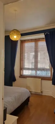 a bedroom with a bed with blue curtains and a chandelier at Brucefield Avenue, Dunfermline in Dunfermline