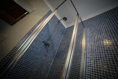 a shower in a bathroom with blue tiles at Bay and Bridge near Edinburgh in Dunfermline