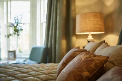 a bedroom with a bed with a lamp and a window at Cairn Lodge in Auchterarder