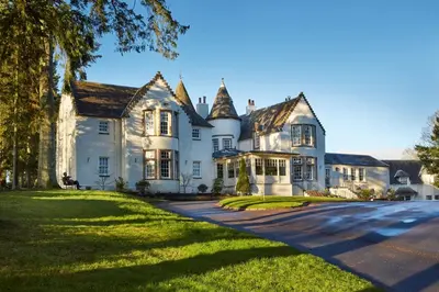 a large white house with a driveway at Cairn Lodge in Auchterarder
