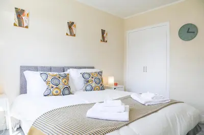 a white bedroom with a bed with towels on it at Netherton House in Wishaw