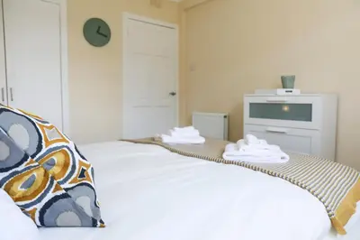a bedroom with a bed with a clock on the wall at Netherton House in Wishaw