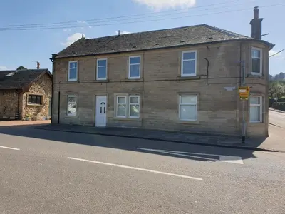 an old brick building on the side of a street at Riverside Apartments in Carluke
