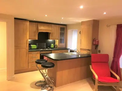 a kitchen with a sink and a red chair in it at Nelson Seaside Apartment in Largs