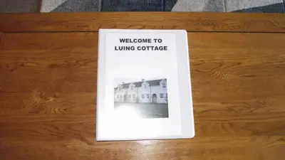a welcome to living concrete book on a wooden table at Craobh Marina Cottages in Craobh Haven
