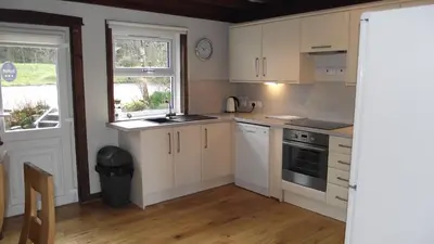 a kitchen with white cabinets and a window at Craobh Marina Cottages in Craobh Haven