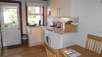 a kitchen with a sink and a washing machine at Craobh Marina Cottages in Craobh Haven