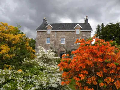 an old stone house surrounded by trees and flowers at Thistle House Guest House in Saint Catherines