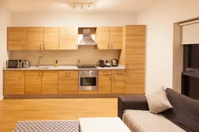 a kitchen with wooden cabinets and a couch in a living room at PREMIER SUITES PLUS Glasgow George Square in Glasgow