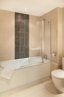 a white bathroom with a tub and a toilet at PREMIER SUITES PLUS Glasgow George Square in Glasgow