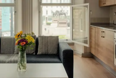 a living room with a couch and a vase of flowers on a table at PREMIER SUITES PLUS Glasgow George Square in Glasgow
