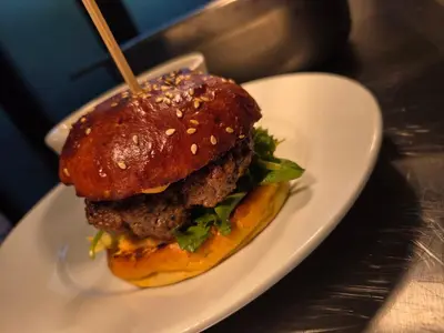 a hamburger on a white plate on a table at The Old Schoolhouse Hotel in Larkhall