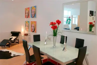 a dining room with a table with red flowers on it at River Clyde West End Apartment - 2 Bedrooms in Glasgow