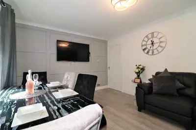 a living room with a table and a couch and a clock at 2 Bedroom Apartment at SECC Hydro FREE PARKING in Glasgow