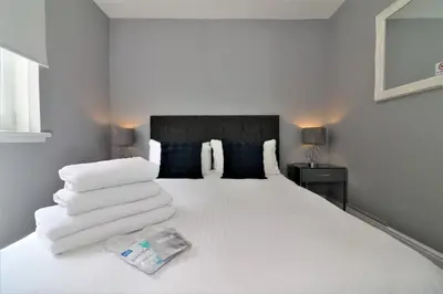 a bedroom with a white bed with towels on it at 2 Bedroom Apartment at SECC Hydro FREE PARKING in Glasgow